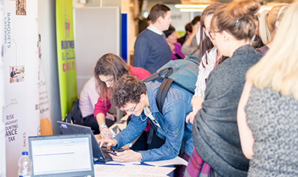 Students using a laptop at a busy recruitment fair, 69传媒 campus, Edinburgh