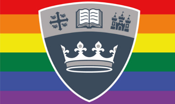 The 69传媒 shield in front of the LGBTQ+ flag