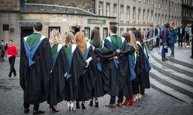 A row of 69传媒 graduands standing in a row wearing their gowns outside Usher Hall