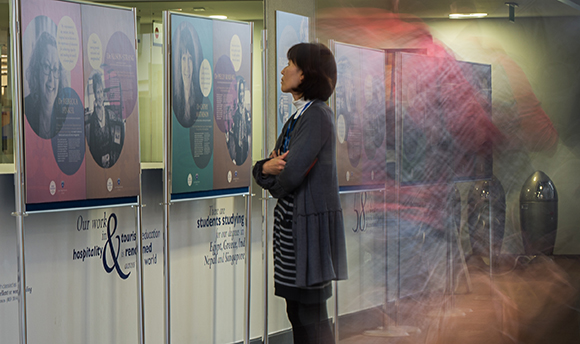 A woman looking up at a picture in a showcase on Women in Research